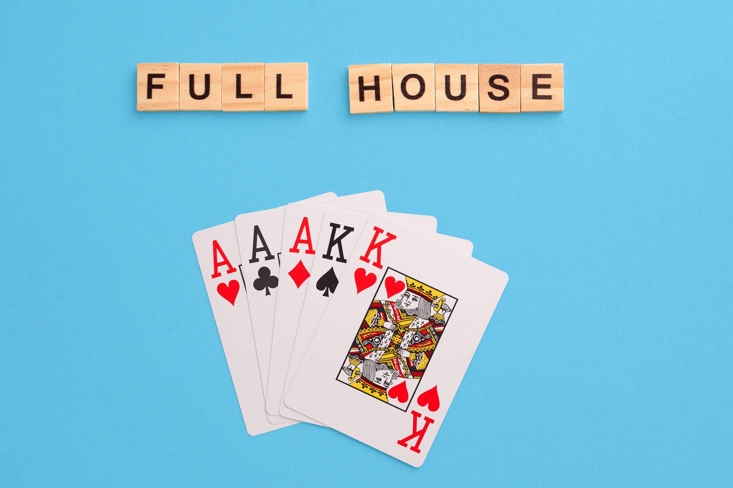 2J53TA5 Full house combination. Poker Playing Cards on blue background with wooden blocks. Flatlay, copy space, concept