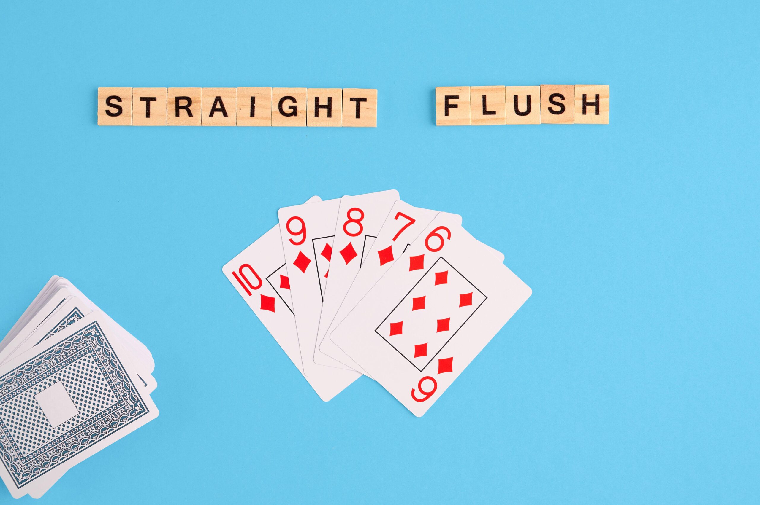2J53TDR Straight flush combination. Poker Playing Cards on blue background with wooden blocks. Flatlay, copy space, concept