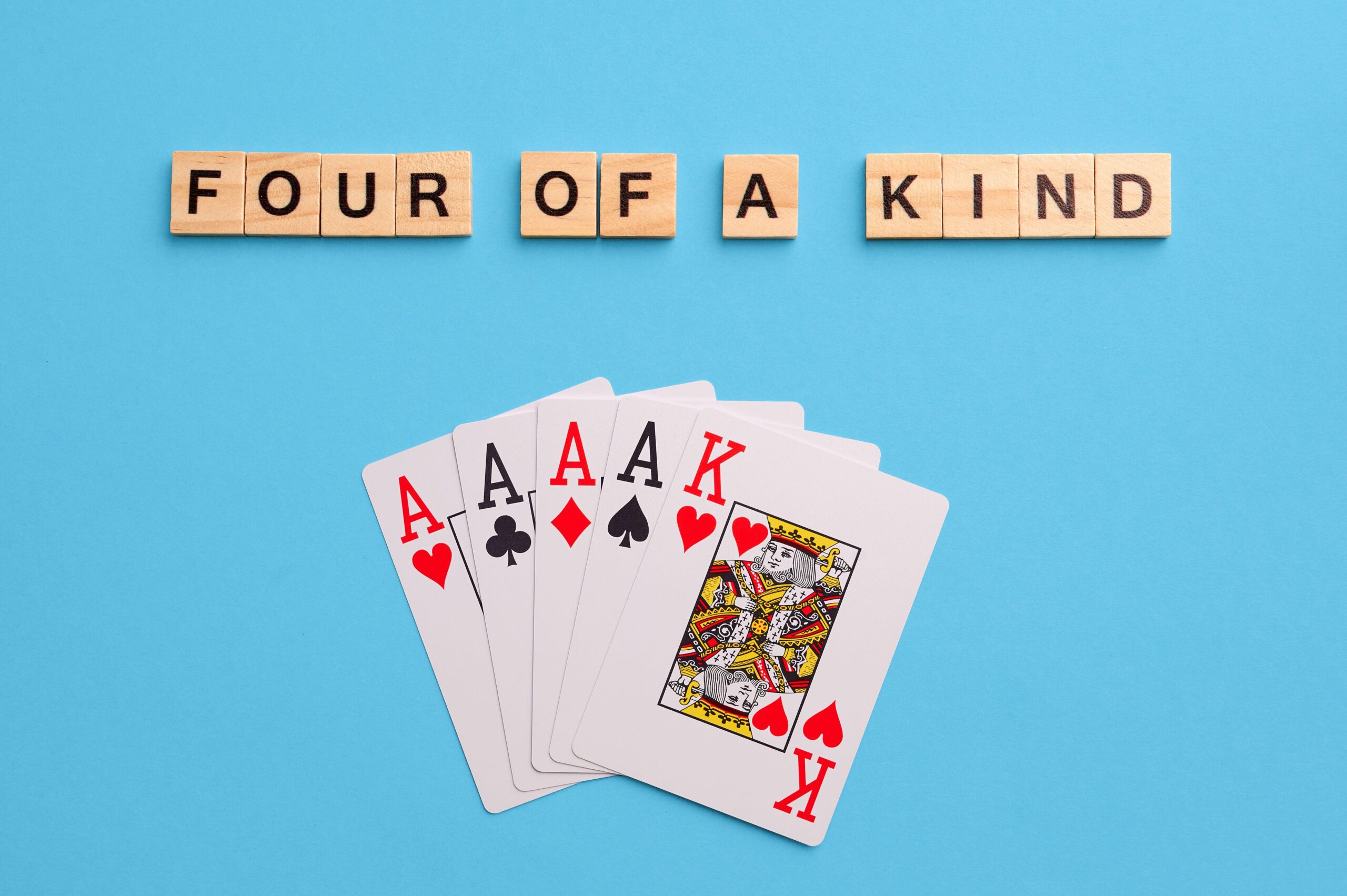2J53TK5 Four of a kind combination. Poker Playing Cards on blue background with wooden blocks. Flatlay, copy space, concept