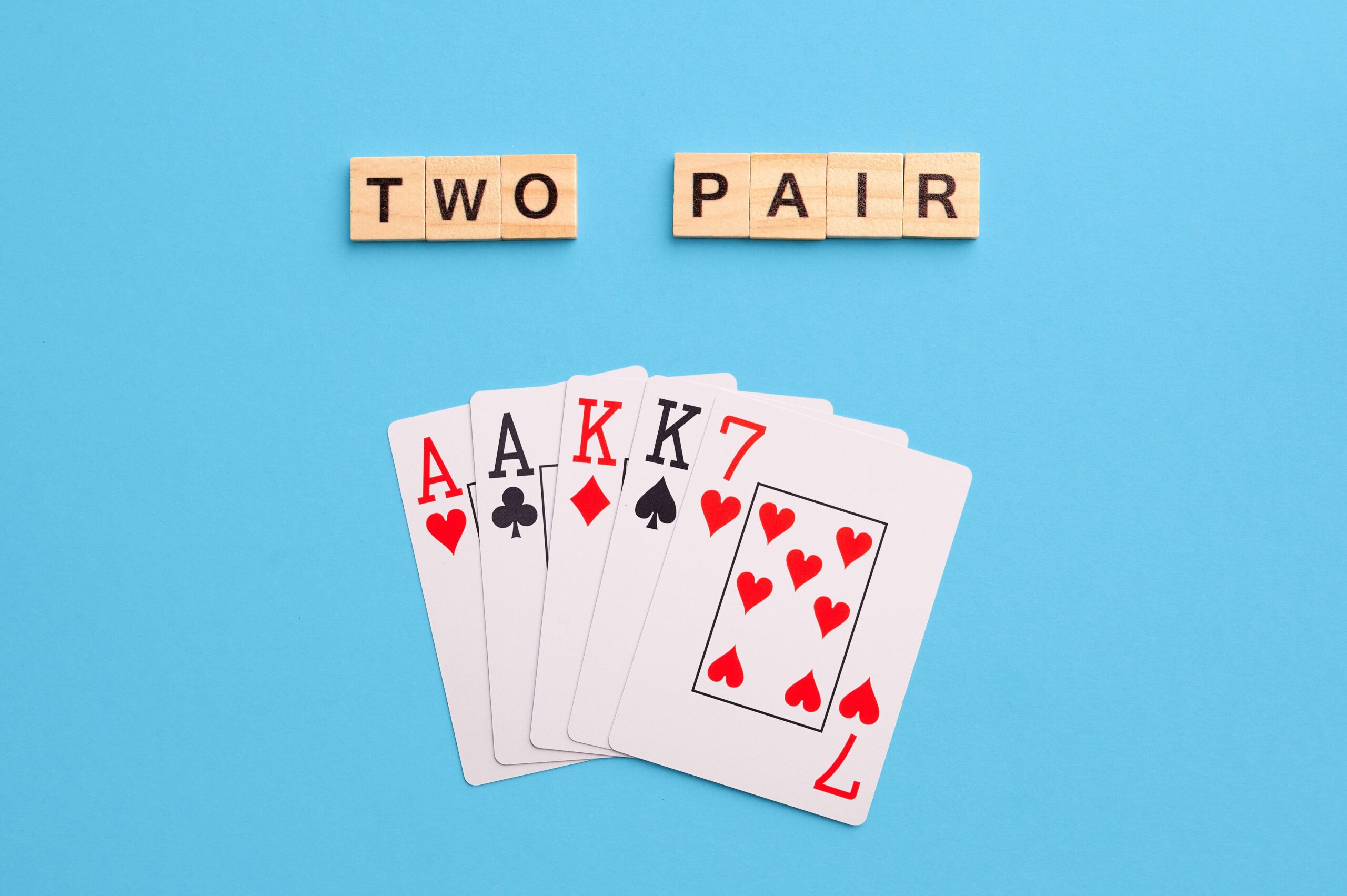 2J53TNA Two pair combination. Poker Playing Cards on blue background with wooden blocks. Flatlay, copy space, concept